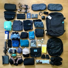 an assortment of travel items laid out on a wooden floor, including backpacks and toiletries