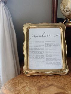 a gold framed sign sitting on top of a wooden table