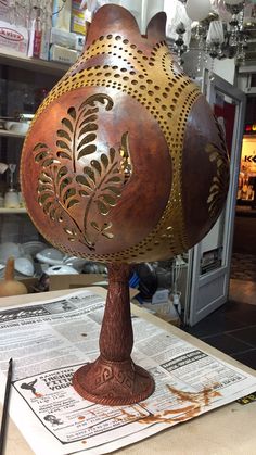 a large metal vase sitting on top of a table next to a newspaper and other items