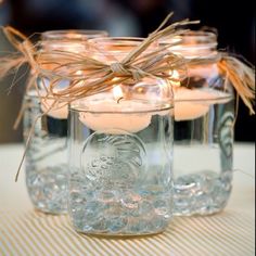 three mason jars filled with candles on top of a table