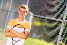 a young man holding a tennis racquet on top of a tennis ball court