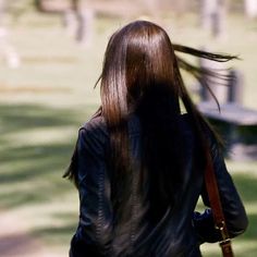 a woman with long hair walking in the park