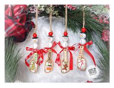 four wooden spoons with snowmen on them hanging from a christmas tree ornament