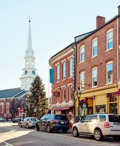 cars parked on the side of the road in front of buildings with a clock tower