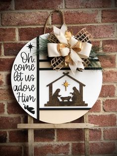 a nativity sign hanging on the side of a brick wall with a ribbon around it