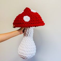 someone is holding up a knitted mushroom with a red and white hat on it