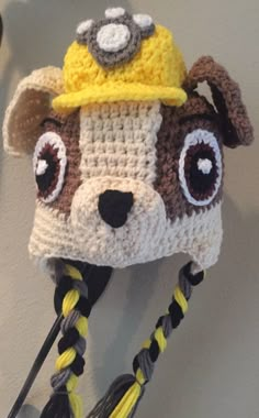 a crocheted hat with a dog's face on it, hanging from a hook