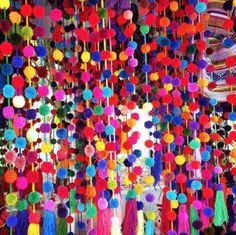 the colorful decorations are hanging from the ceiling in front of the building with many pom - poms on it