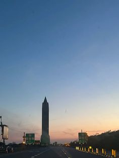 the sun is setting on an empty highway with tall buildings in the backgroud