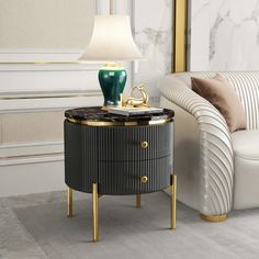 a black and gold side table with a lamp on it next to a white couch