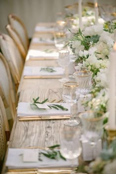 a long table with white flowers and greenery is set up for a formal dinner