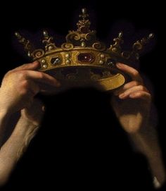 a person holding up a golden crown in the dark with their hands on top of it