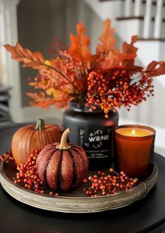 a table topped with candles and pumpkins on top of a black plate covered in berries