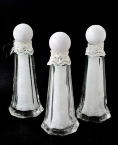 three glass salt and pepper shakers with lace on the top one has an egg in it