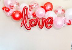 balloons are arranged in the shape of letters that spell out love on a white wall