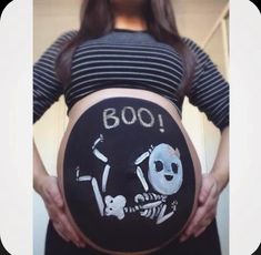 a pregnant woman holding her belly painted with skulls and bones