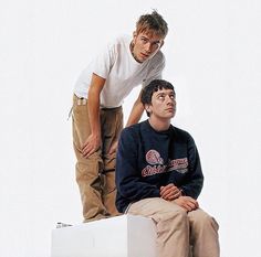 two young men sitting on top of a white box while one looks up at the sky