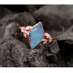 a blue ring sitting on top of a rock covered in dirt and ice flakes