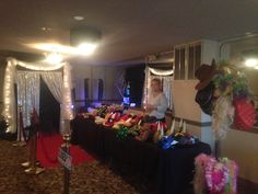 a woman standing in front of a table filled with hats and other items at a party