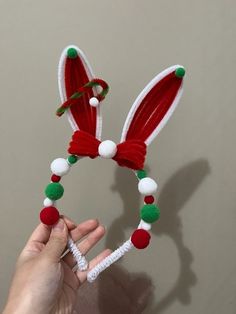 a hand holding up a red and white bunny ears headband