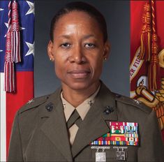 a woman in uniform standing next to flags