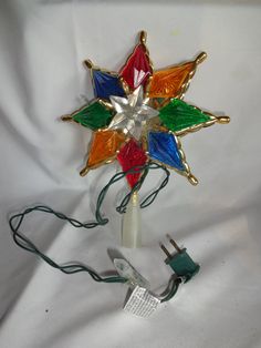 a multicolored glass star ornament on a white background with wires and plugs