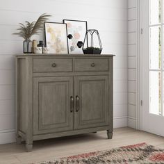 a gray cabinet with two doors and some pictures on it's top, next to a rug