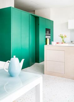 a tea pot sitting on top of a table next to a kitchen counter and cupboards