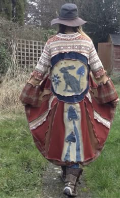 a woman walking down a path wearing a dress with an animal on it's back