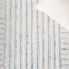 a white and blue striped rug next to a pillow