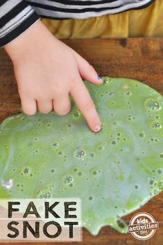 a person touching a green leaf with their finger on it that says fake snot