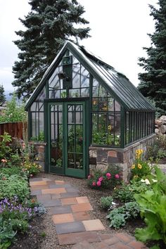 a small green house sitting in the middle of a garden