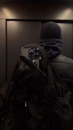 a person wearing a hoodie taking a selfie in front of a mirror