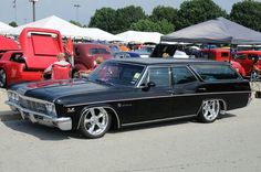 an old black car parked next to other cars in a parking lot at a car show