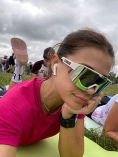 a woman in pink shirt laying on top of a green blanket next to other people