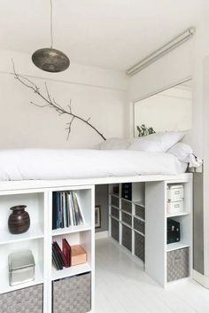 there is a bed with white sheets and bookshelves in the room, next to an open bookcase