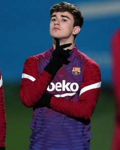 a young man standing on top of a soccer field wearing a purple and red uniform