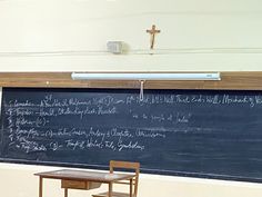 a blackboard with writing on it and a wooden table in front of it,