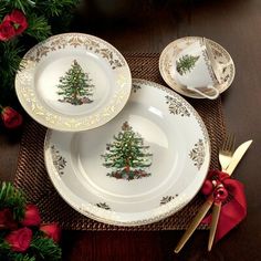 three plates with christmas trees on them sitting on a place mat next to red roses