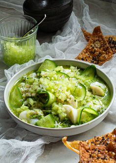 a white bowl filled with cucumber and other food on top of a table