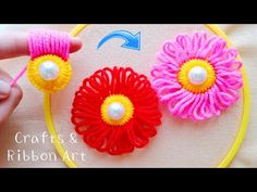 three crocheted flowers with pearls in the center on a piece of fabric next to a yellow hoop