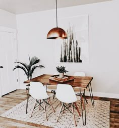 a dining room table with four chairs and a potted plant in the corner on top of it