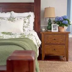 a bedroom with a bed, night stand and flowers on the nightstand next to it