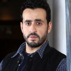 a close up of a person wearing a vest and looking at the camera with a serious look on his face