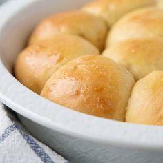 a white bowl filled with rolls on top of a blue and white towel