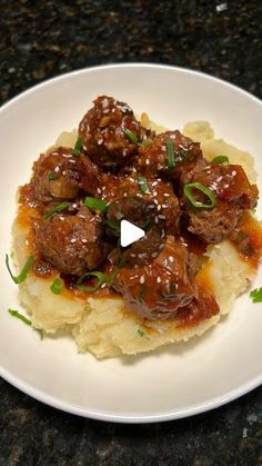 a white plate topped with meatballs and mashed potatoes on top of a counter