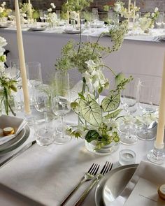 the table is set with white flowers and silverware