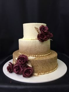 a three tiered wedding cake with purple flowers on the top and gold trimmings