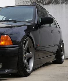 a black car parked next to a white wall