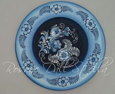 a blue and white plate with flowers painted on the front, sitting on a wall